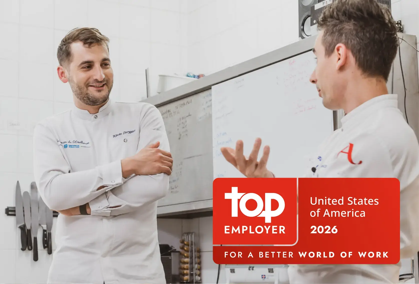 In the background, two chefs having a conversation. In the foreground, badge for top employer award from the for a better world of work organization, in the united states of America region in 2026.